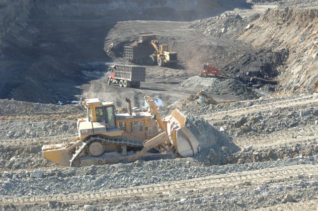 Heavy earthmoving equipment during reclamation of the abandoned Horse Creek coal mine near Pinckneyville, Illinois, with a bulldozer in the foreground and dump trucks working in the excavation behind it.